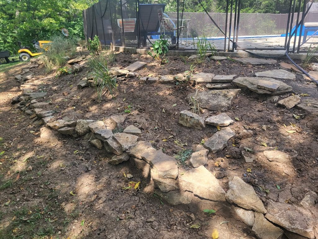 Before photo of the slope with rocks scattered around and uneven terrain